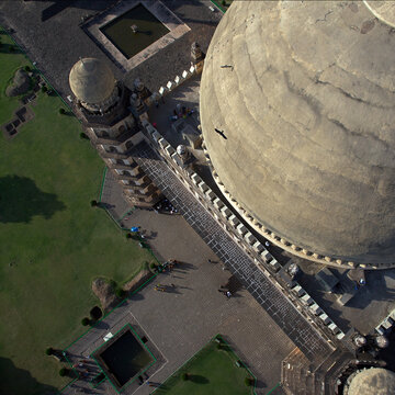 Aerial view of the majestic Gol Gumbaz dome casting shadows on the courtyard below, creating a tapestry of light and shade, Bijapur, Karnataka, India.