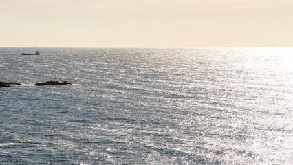 Cargo ship on a shimmering sea under a sunset sky
