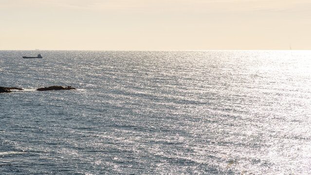 Cargo ship on a shimmering sea under a sunset sky