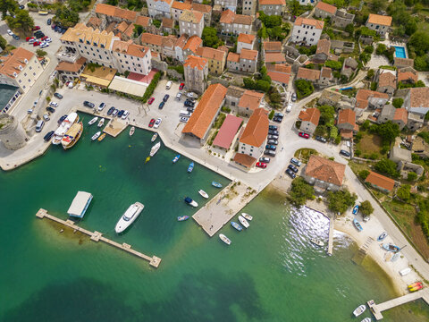 Aerial view of the vibrant harbour dotted with boats, nestled against the terracotta rooftops of the town's buildings, Mali Ston, Dubrovnik-Neretva County, Croatia.