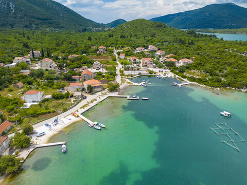 Aerial view of boats gently bobbing on the turquoise waters of the bay near the village, framed by lush green hills, Mali Ston, Dubrovnik-Neretva County, Croatia.