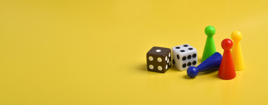 Colorful game chips and two dice isolated on a yellow background, banner, space for text