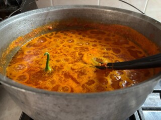 Traditional homemade adjika sauce simmering in a cast iron cauldron, rich red color and aromatic spices. Perfect for culinary, Georgian cuisine, and rustic cooking themes
