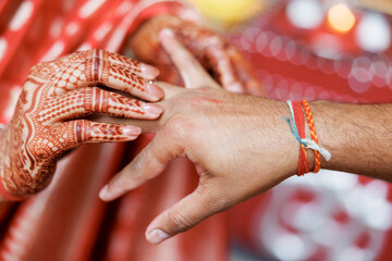 Close-up of bride's hands with mehendi putting wedding ring on groom. Traditional Indian wedding...