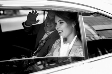 bride and groom with a black car
