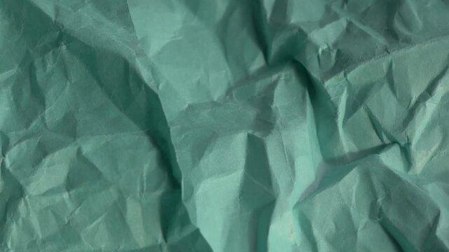 Crumpled green paper texture features detailed folds and shadows, perfect for use in backgrounds, design projects, and artistic endeavors. crumpled green paper 