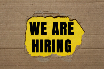 We are hiring message written on ripped torn cardboard paper on yellow background. Conceptual we...