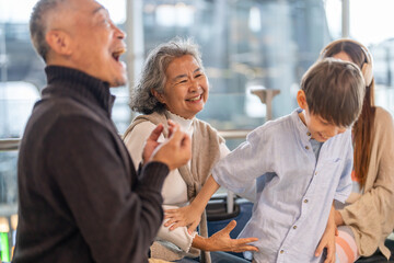 Obraz premium Asian multigenerational family at airport traveling with kids and grandparents, joyful moments of vacation, family holiday trip with luggage before flight, tour, friendly airline, hotel for families