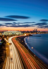 Dynamic cityscape with blurred car lights along the sea at twilight hour