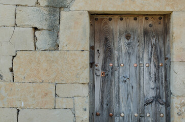 Front view of antique wooden damaged broken door with brown wood texture and metallic rusty vintage handle and keyhole and bolts from a spain village. Horizontal photo background with copy space