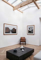 Fototapeta premium A bright and minimalist art gallery interior featuring a high vaulted ceiling, white walls, and framed artwork for a serene and contemplative viewing experience. 