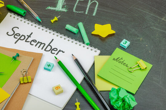 Back to school stationery concept with sunflower, notebook and “September” text on chalkboard