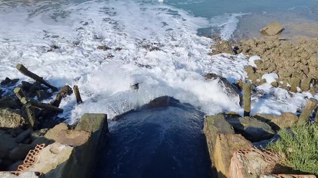 Powerful water flows through floodgates in the Salinas de Carboneros marshes, in Chiclana de la Frontera, C&aacute;diz, Andalusia, Spain.