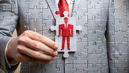 Businessman holding a puzzle piece with a person icon, symbolizing finding the right fit in a team or organization