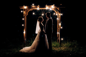 bride and groom against the backdrop of an evening wedding arch