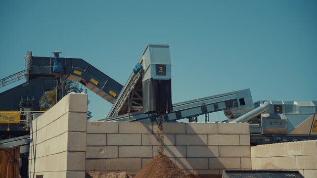 Dirt sortiment falling at an outdoor construction waste sorting facility on a sunny day
