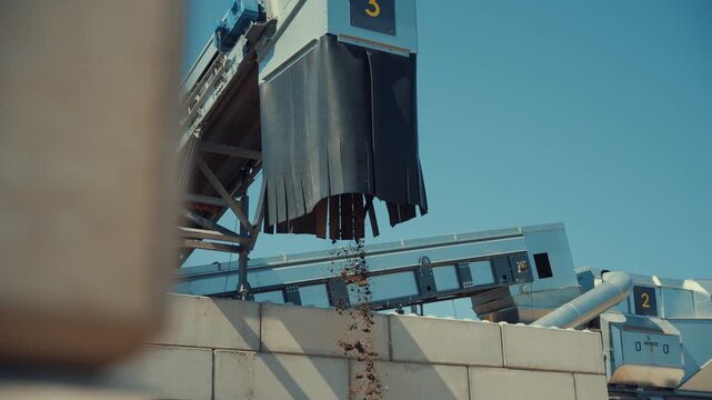 Dirt sortiment falling at an outdoor construction waste sorting facility on a sunny day