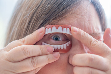 Dental retainers, Surreal portrait where artificial dentures frame human eye, creating unusual...
