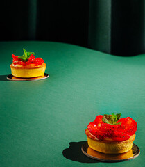 Colorful fruit tarts on a green table showcase delicious dessert artistry