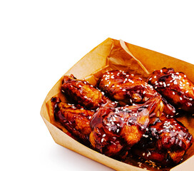Crispy chicken wings topped with savory sauce and sesame seeds served in a box