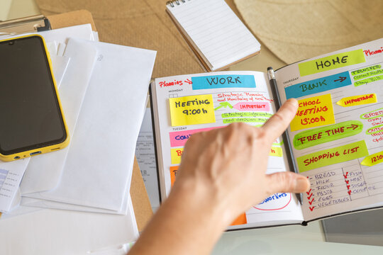 Manager is checking schedule in a personal organizer full of colorful sticky notes, planning work meetings, errands, and free time activities