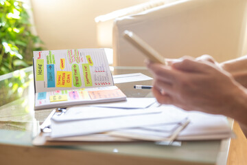 Woman is using smartphone and personal agenda to organize work, school meetings, free time and...