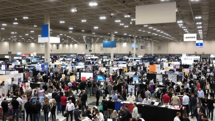 A busy trade show bustling with attendees, showcases the latest in industry innovation and networking opportunities within a vast exhibition hall.