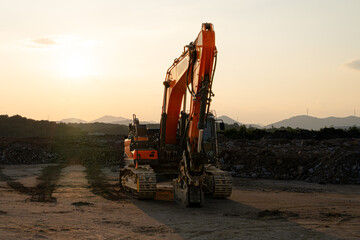 A powerful excavator rests at a construction site during golden hour, surrounded by dirt and rocky...
