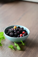 Close-up macro view of a bowl with fresh seasonal fruits — blackberries, blueberries, and mint. A vibrant and healthy mix of summer berries, perfect for fresh eating, healthy lifestyle, and food photo