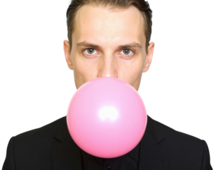 A man in a black suit blows a large pink bubblegum bubble, creating an eye-catching and playful contrast.