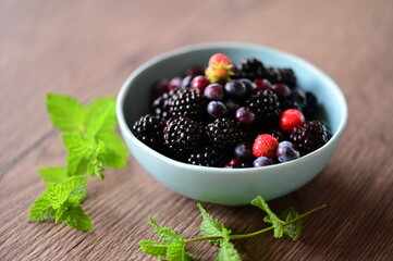 Close-up macro view of a bowl with fresh seasonal fruits — blackberries, blueberries, and mint. A vibrant and healthy mix of summer berries, perfect for fresh eating, healthy lifestyle, and food photo