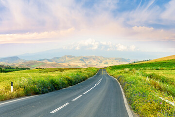 beautiful landscape of long road to amazing mountain scene from a green summer fields and hills....