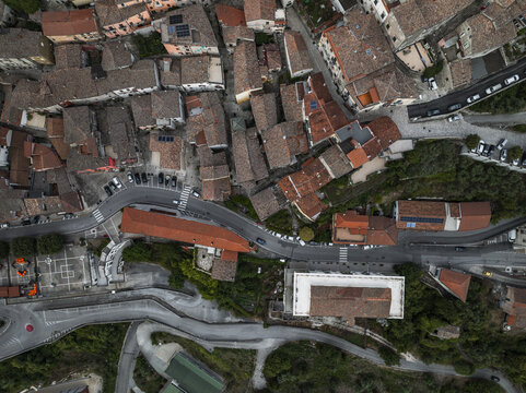 Aerial view of terracotta rooftops cascading down the hillside, winding roads carving through the ancient settlement nestled amidst verdant trees, Morcone, Benevento, Campania, Italy.