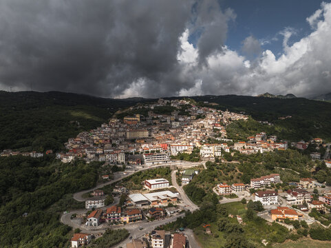 Aerial view of the town nestled amongst rolling hills, caught between the shadows of gathering clouds and the bright promise of sunlight, Morcone, Benevento, Italy.
