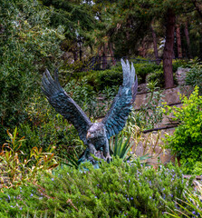 Antique bronze eagle in the park among the greenery.
