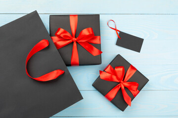 Black shopping bag and gift boxes on wooden background, top view. Black Friday concept