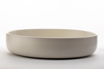 A clean, minimalist shot of an empty, shallow ceramic bowl in a neutral white or cream color,...