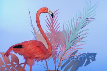 Colorful flamingo and monstera leaf decoration against blue background