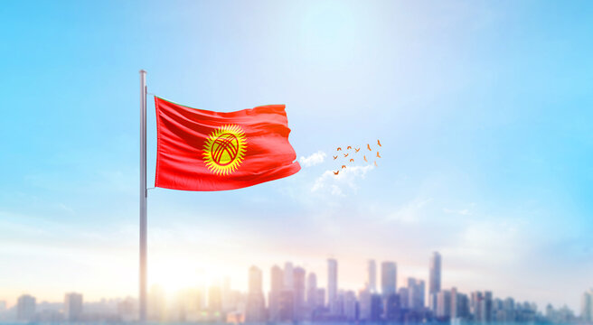 Kyrgyzstan national flag waving with skyline and buildings. Kyrgyzstan national flag for independence day. - Powered by Adobe