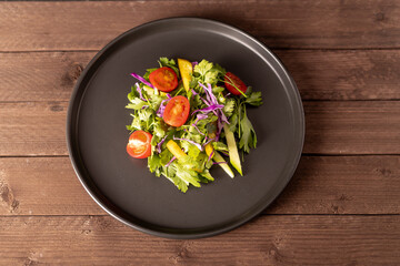 Plate with fresh salad: colorful mix of lettuce, tomatoes, cucumbers, and carrots drizzled with vinaigrette