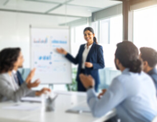 Obraz premium Smiling female entrepreneur presenting ideas to a diverse business team in a modern office, captured with a blurred background