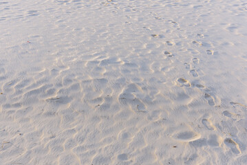 Footprints on a sandy beach with ripples from wind in the sand