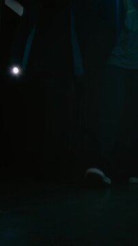 Vertical shot of two thieves in total black with turned on flashlights in hands examining apartment during housebreaking