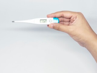 Obraz premium Close-up of a hand holding a digital thermometer, displaying a temperature reading. Illustrating health, illness, and medical care for a healthcare context.