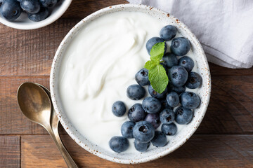 Greek yogurt and blueberries bowl on wooden table background, healthy food