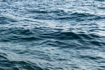 Naklejka premium abstract close-up of gently moving sea surface. calm water surface with waves in deep blue tones. liquid pattern. soothing