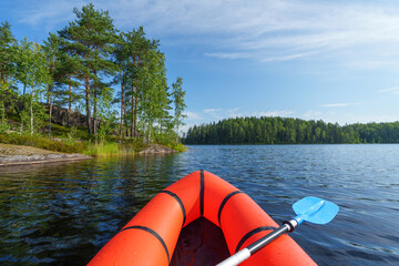 Orange packraft on a beautiful summer lake.