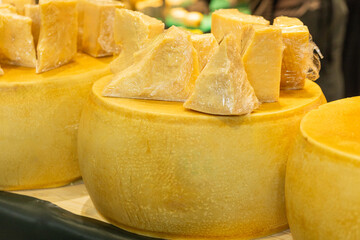 Cheese wheels with cut pieces displayed at a market showcasing fresh dairy products and textures