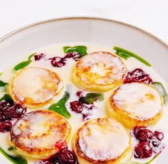Savory cottage cheese pancakes with berry sauce and spinach on a plate