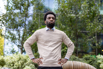 Portrait of a confident man in a light sweater outdoors, surrounded by nature.